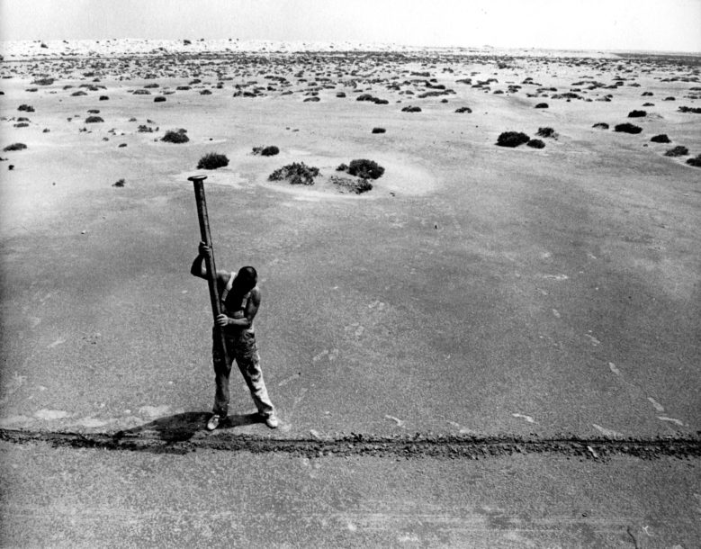 Photograph of Günther Uecker with large nail in the desert